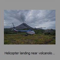 Helicopter landing near volcanologists hut, Karymsky volcano behind